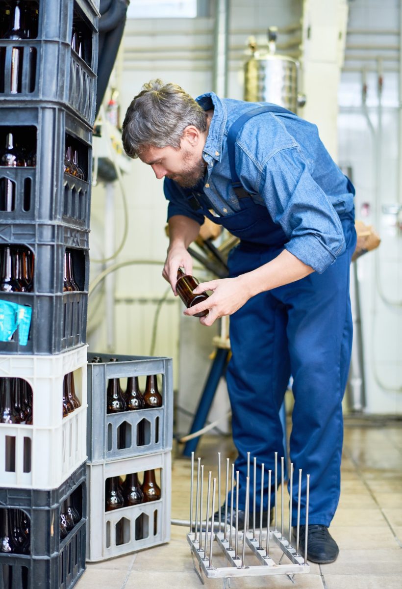 modern-brewery-worker-preparing-beer-bottles-for-loading.jpg Hombre preparando botellas de cerveza en la bodega
